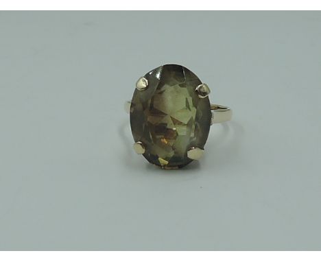 A lady's dress ring having an oversized yellow/brown oval stone in a four claw basket mount on a 9ct gold loop,  size L