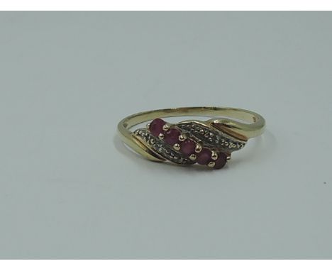 A lady's dress ring having a row of ruby style stones in a swirl illusionary mount on yellow metal loop stamped 9K,  size R