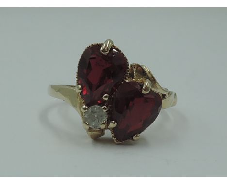 A lady's dress ring having two ruby style teardrop stones in claw set heart mounts with a clear paste stone between two mould