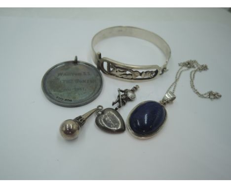 An Egyptian silver tension bangle having decorative panel, a silver medal, Lapis Lazuli pendant in white metal mount and thre