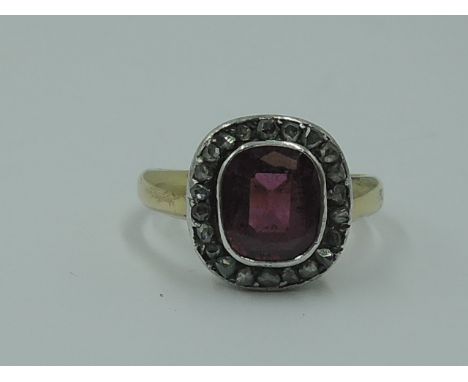 A lady's dress ring having a central pink stone possibly tourmaline in a collared mount with diamond chip surround on a yello