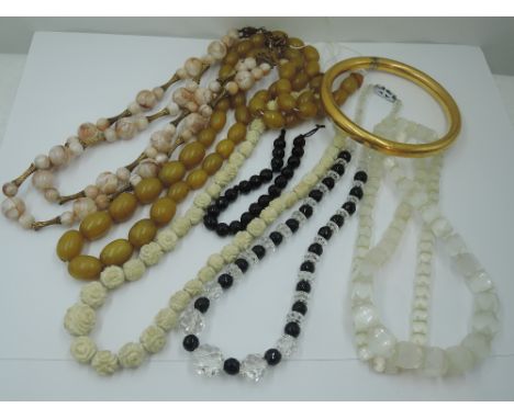 A small selection of vintage strings of beads including carved bone, crystal and jet, carved opaque glass, bakelite amber sty
