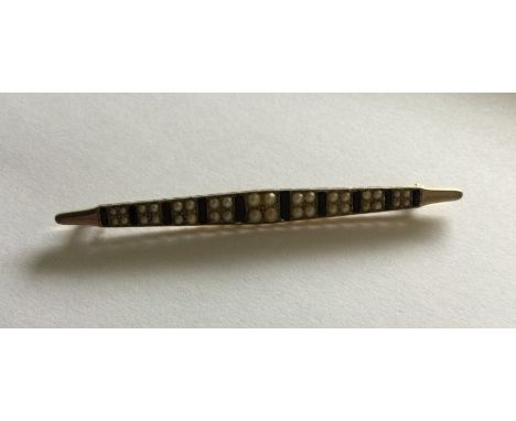 A stylish onyx and pearl brooch in two colour gold. Approx. 10 grams. Est. £150 - £200.