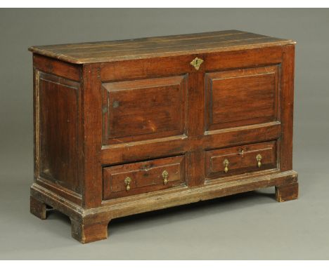 A George III oak mule chest, with two panels to the front with two drawers beneath with brass drop handles and raised on brac