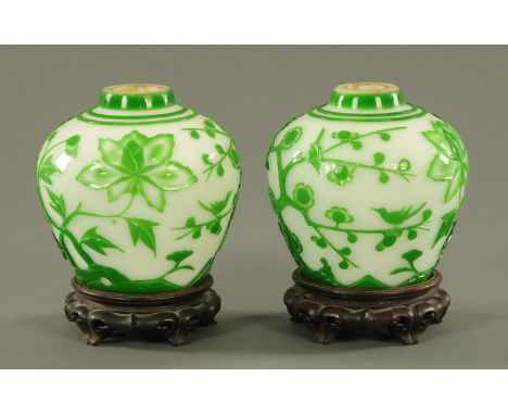 A pair of Chinese Peking style glass vases, 20th century, decorated in relief with blossoming prunus and peony, on wood stand