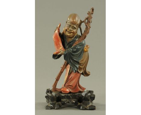 A Chinese carved wood painted figure of Shou Lao, late 19th/early 20th century, carved holding a scroll, his gnarled staff le