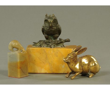 A bronze owl paperweight, raised on a yellow variegated marble stand, length 11 cm, brass hare and soapstone bird.