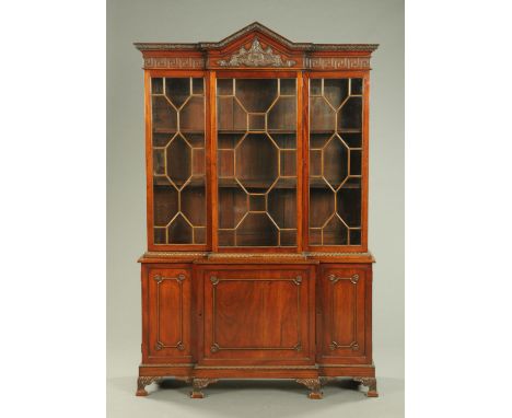 An Edwardian mahogany breakfront bookcase, with triangular pediment, Greek key moulded frieze and glazed upper doors, the bre