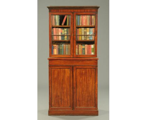 An early Victorian mahogany bookcase, the top half with moulded cornice above a pair of glazed doors, the base fitted with on