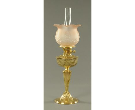 A late Victorian brass oil lamp, with integral brass reservoir with moulding and with tinted pink glass shade.  Height includ