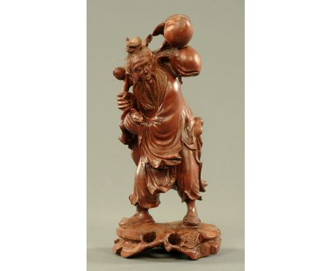A Chinese hardwood figure of a peach seller, late 19th/early 20th century, a bearded figure wearing long robes and sandals an