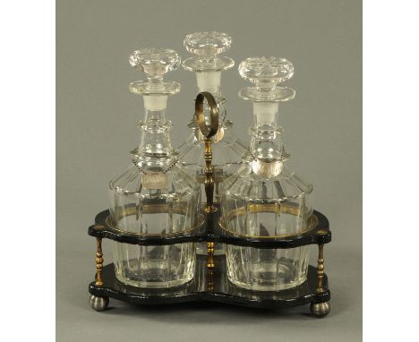 A lacquered trefoil decanter stand, 19th century, with brass mounts and supports housing three spirit decanters with silver w