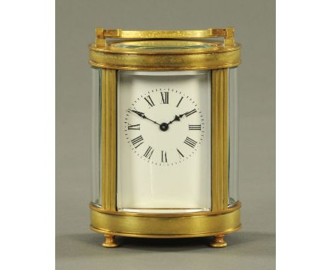A French brass oval cased carriage clock timepiece, circa 1900, with bevelled glass and enamel dial with Roman numerals.  Hei