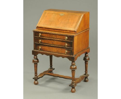 A William & Mary style walnut bureau, raised on cup and cover legs with low stretchers and bun feet.  Width 58 cm. 