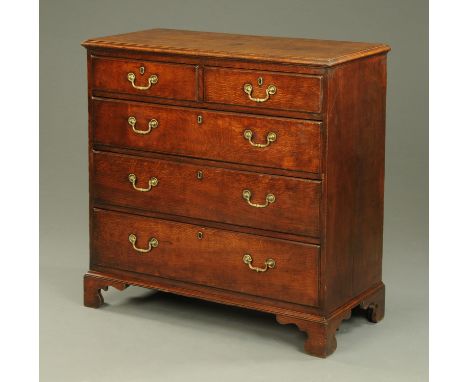 A George III oak chest of drawers, with moulded edge above two short and three long graduated drawers with brass drop handles