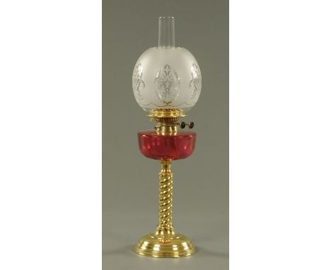 A late Victorian brass oil lamp, with faceted cranberry glass reservoir and etched shade.  Height including chimney 66 cm. 