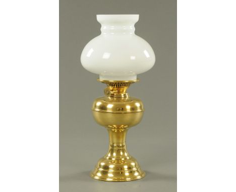 A brass oil lamp, with integral reservoir and milk glass shade.  Height 44 cm. 