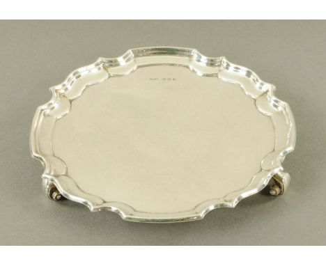 A silver card tray, Harrison Fisher & Co. Sheffield 1979, with raised and shaped rim, raised on three scrolling feet.  Diamet