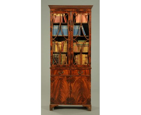A mahogany bookcase on cupboard, with carved and moulded pediment above glazed cupboard doors with rosewood veneered glazing 