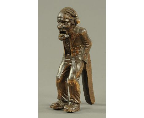 A Black Forest carved softwood nutcracker, first half 20th century, carved as a hunched over figure with his hands in his tro