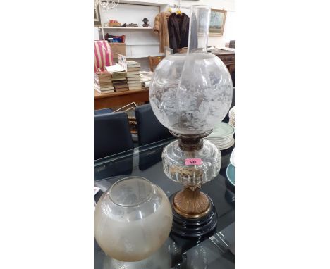 A Victorian oil lamp having a clear glass reservoir and two etched shades standing on a black glass baseLocation: 