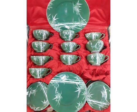 A Japanese green ground tea set with white images of bamboo, 10 setting, housed in a vintage wooden box with red fitted inter