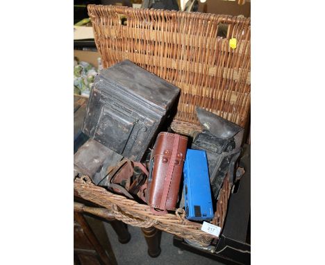 A WICKER BASKET OF VINTAGE CAMERAS TO INC A POPULAR PRESSMAN PLATE CAMERA A/F