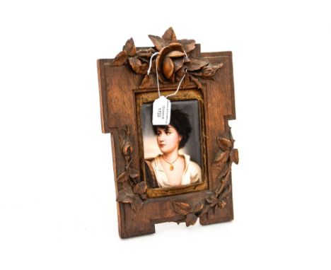 A portrait on porcelain, oblong,  a young boy with a medallion possibly German/Austrian, placed within a carved Black Forest 