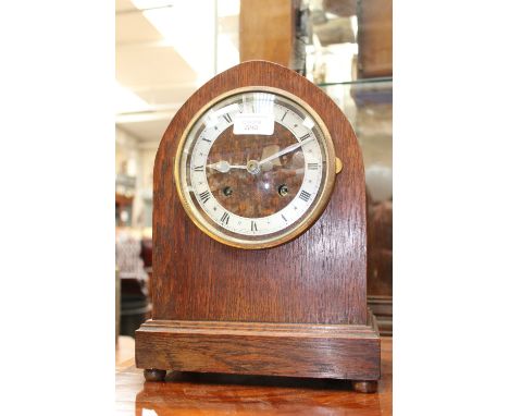 An early 20th Century oak cased mantel clock, lancet arched form with silvered chapter ring 