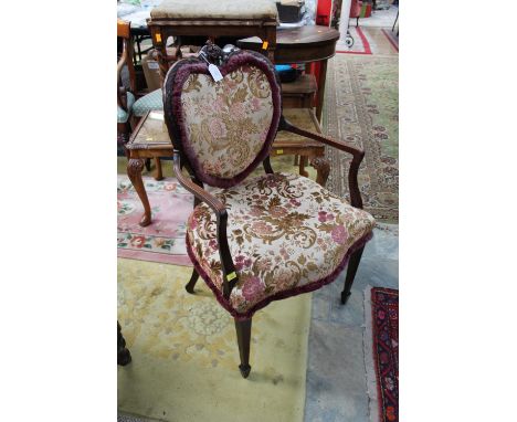 A Edwardian mahogany ladies' open armchair, with a heart shaped padded back, overstuffed seat, raised on square tapering legs