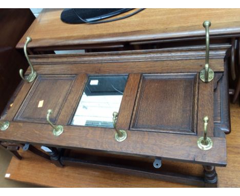 An early 20th Century oak cloak stand, the centre inset with a mirror