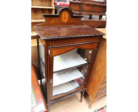 An Edwardian mahogany display cabinet, having an inlaid top rail, the single glazed door opening to reveal a fitted shelf, ra