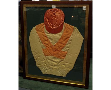 A 20th Century framed pink silk jockey's cap and pink and white silk jacket, tied to the back of the frame is a deep pink sil