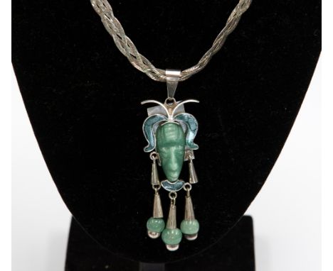 A Mexican jade, malachite and silver pendant in the form of an Aztec mask, having carved jade mask to the centre, malachite s