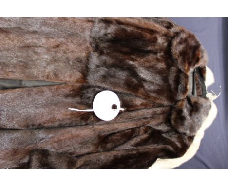 A dark brown mink long jacket with waist belt and pointed lapels collar, wide cuffs with interesting button detail, lining in