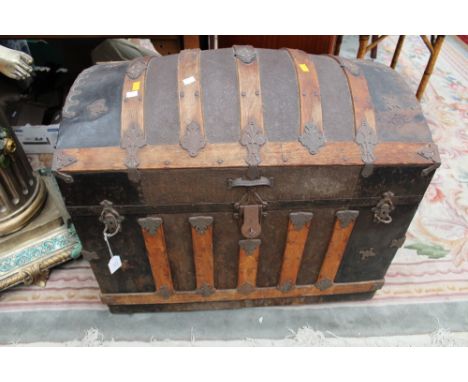 A Victorian dome top cabin trunk, wooden bound with embossed metal decoration, the interior fitted with an arrangement of com