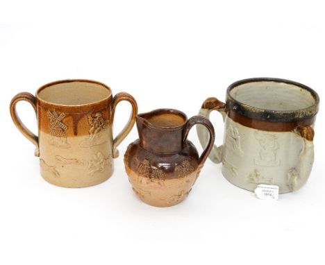 An early 20th Century stoneware loving cup with raised hunting scenes, together with a matching jug and a stoneware tyg, meta