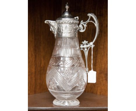 An electroplate mounted cut glass claret jug of baluster form with scroll handle, mask spout, scroll and foliate decoration a