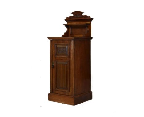 Edwardian carved walnut bedside cupboard having a raised back fitted an open shelf, carved fielded panel door and standing on