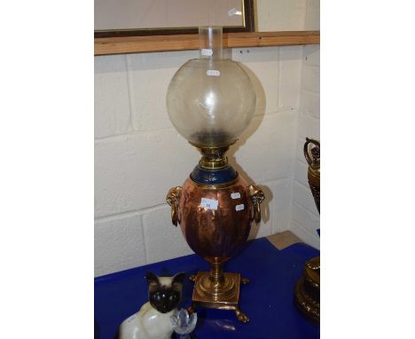 An oil lamp with bulbous copper body and frosted glass shade