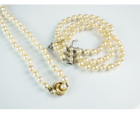 A single strand cultured pearl necklace, the pearl set yellow metal clasp stamped '585', 44cm long, together with a three str
