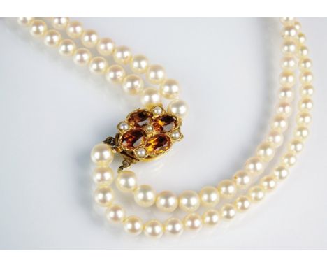 A two strand uniform cultured pearl collarette, with 9ct gold orange topaz and seed pearl set clasp, 30.5cm long