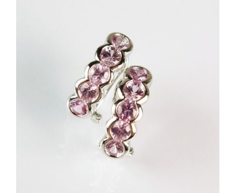 A pair of pink sapphire earrings, each designed as a row of five round mixed cut pink sapphires collet set in white metal wit