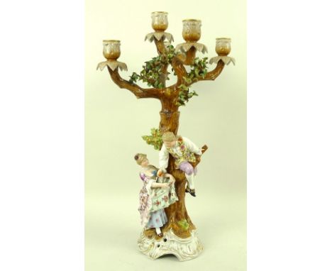 A Sitzendorf porcelain figural five branch candlestick, 19th century, modelled as a young man climbing a tree, passing down a