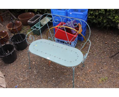 A metal two seater garden bench with pierced seat and wrought metal back rest