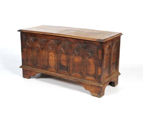 A carved Gothic coffer. The hinged top above panels of Gothic arches enclosing trefoils to front and side panels, on bracket 
