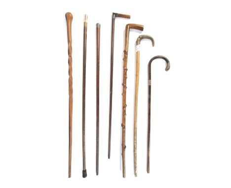 A collection of seven 19th century and later walking sticks and canes, including silver topped examples. Comprising: a malacc