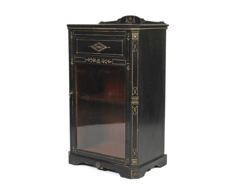 An Edwardian ebonised pier cabinet. Decorated with carved gilt details, the glazed door opening to reveal two shelves, raised