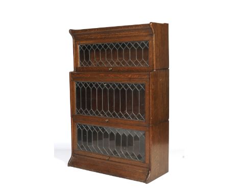 An early 20th century Globe Wernike stained oak glazed three tier bookcase. With leaded astragal glazed hinged doors, on plin