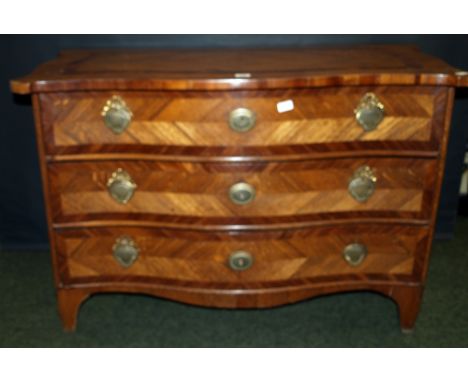 An 18th century Flemish oak and mahogany commode chest of three serpentine-fronted drawers, quartered veneered panels to the 
